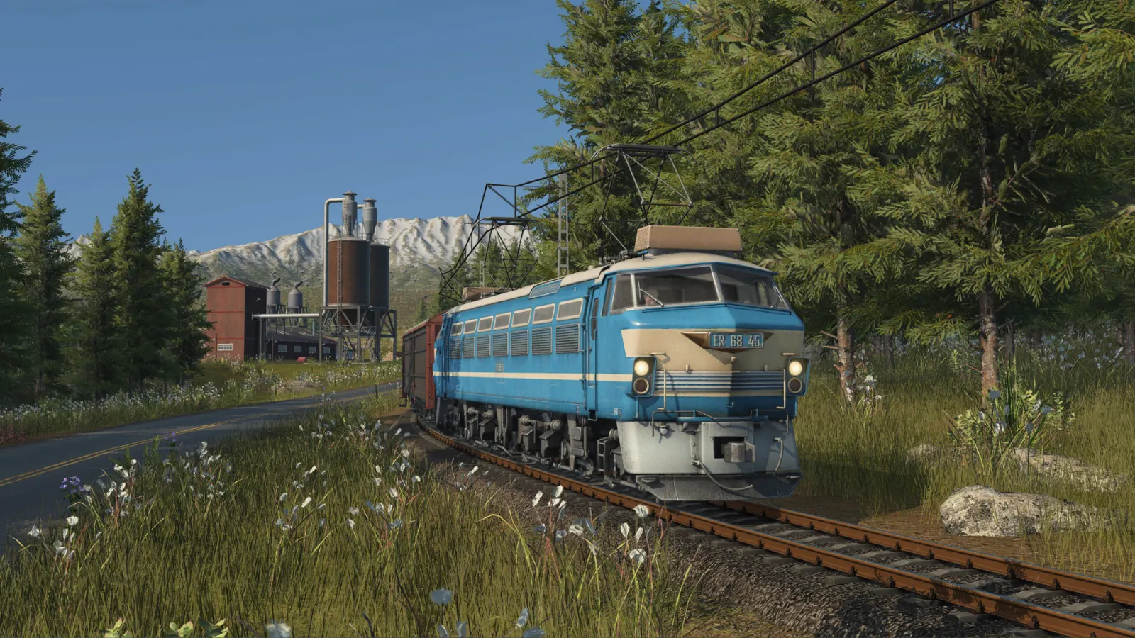 Blue electric freight train passing a forest industry in Transport Fever 3